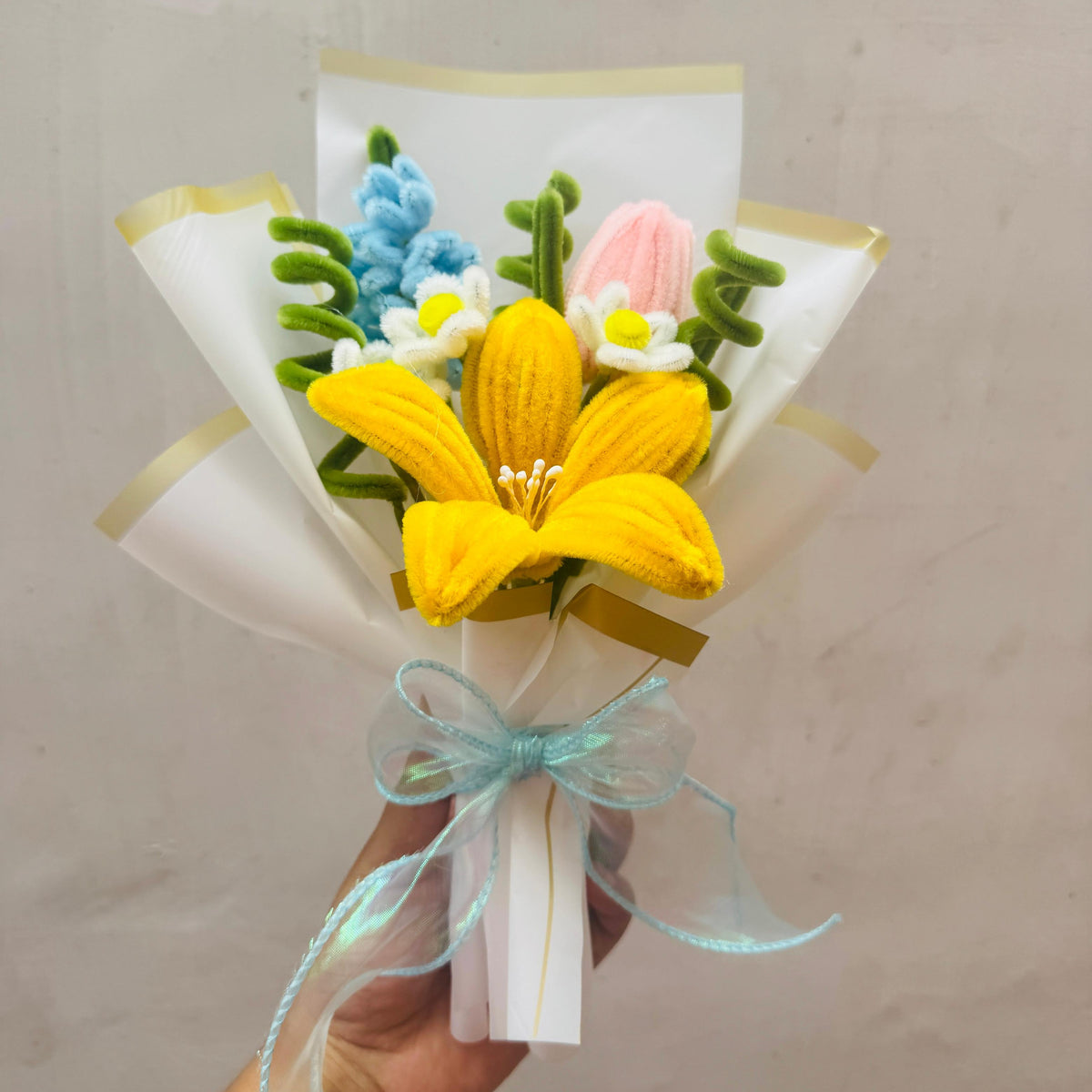 Bouquet of artificial flowers with a yellow center held against a plain background
